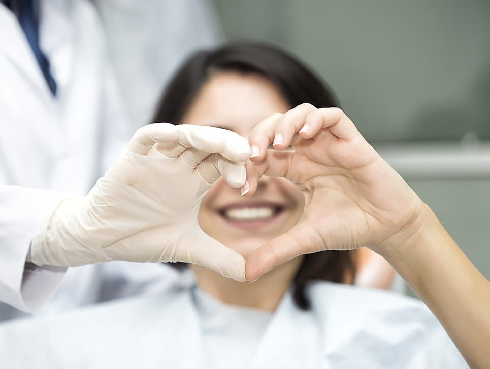Woman and her orthodontist forming a heart with their hands