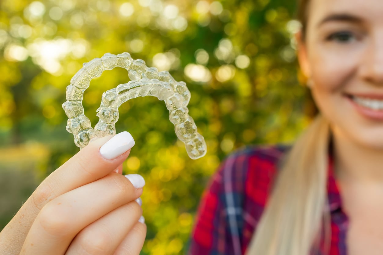 Close up of a pair of clear aligners in Hendersonville, TN being held in the right hand of a woman