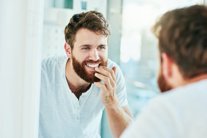 Man admiring the results of his orthodontic treatment in the mirror
