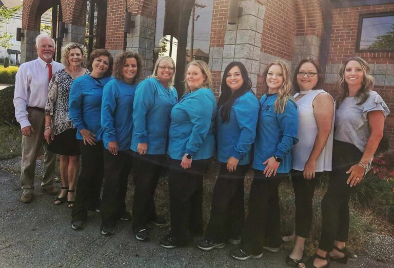 Picture of the Koen Orthodontics team side by side outside of a brick building on an overcast day