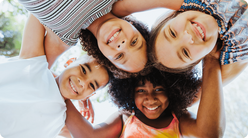 Circle of 4 children smiling and looking down at the camera