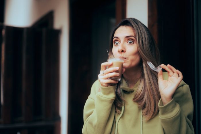 Coffee lover removing her invisible braces afraid of staining it