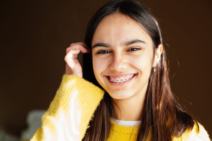 a happy teen girl with braces and some acne smiling at home with the sun coming through the window