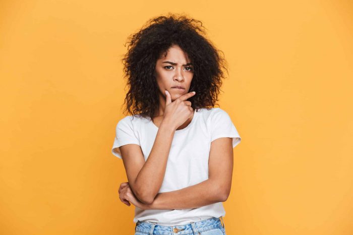 Portrait of a thoughtful young african woman looking at camera isolated over beige background