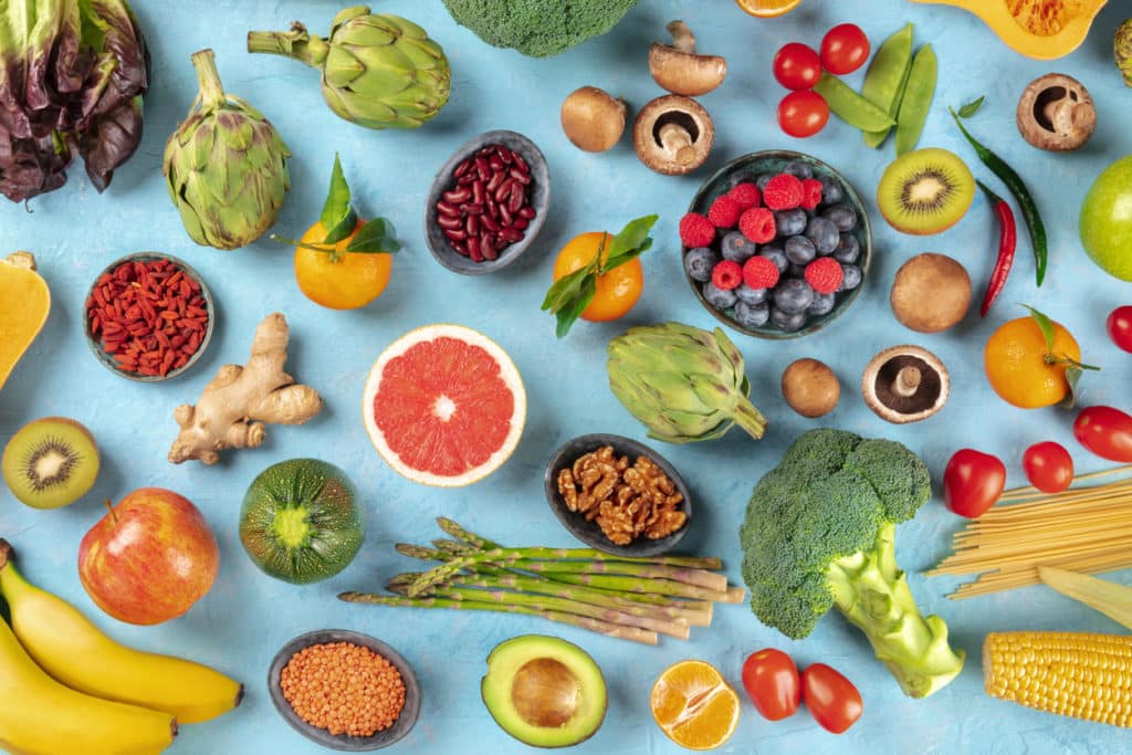 a top view of a table with many different fruits, greens, and other healthy food choices
