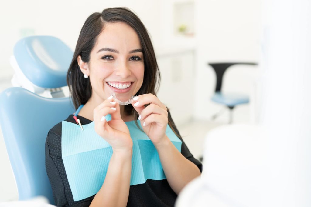 an orthodontist patient sitting at the orthodontists office holding her invisalign