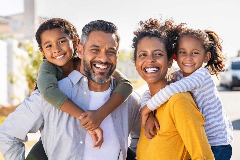 A family portrait of two adults holding their children on their backs