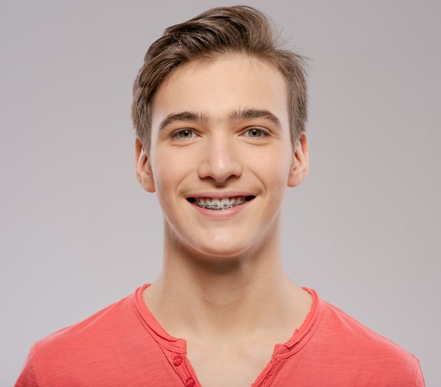 Headshot of teen boy smiling with metal braces