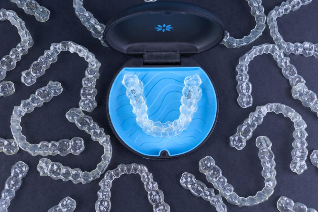 top view of many invisalign clear aligners and their holding case