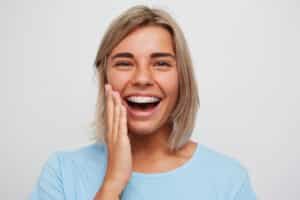 a woman with short hair smiling to show off her clear braces