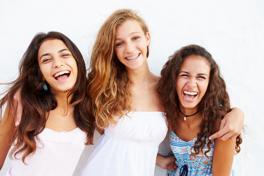 three young woman with great smiles standing in front of a white background.