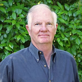 Headshot of Dr. Koen in front of a tall green hedge